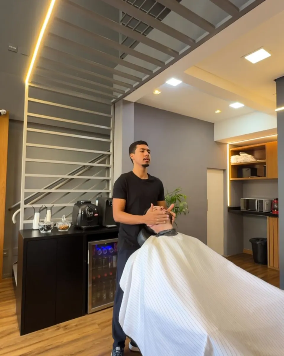 Barbeiro atendendo um cliente na cadeira, no salão do Garimpo Studio