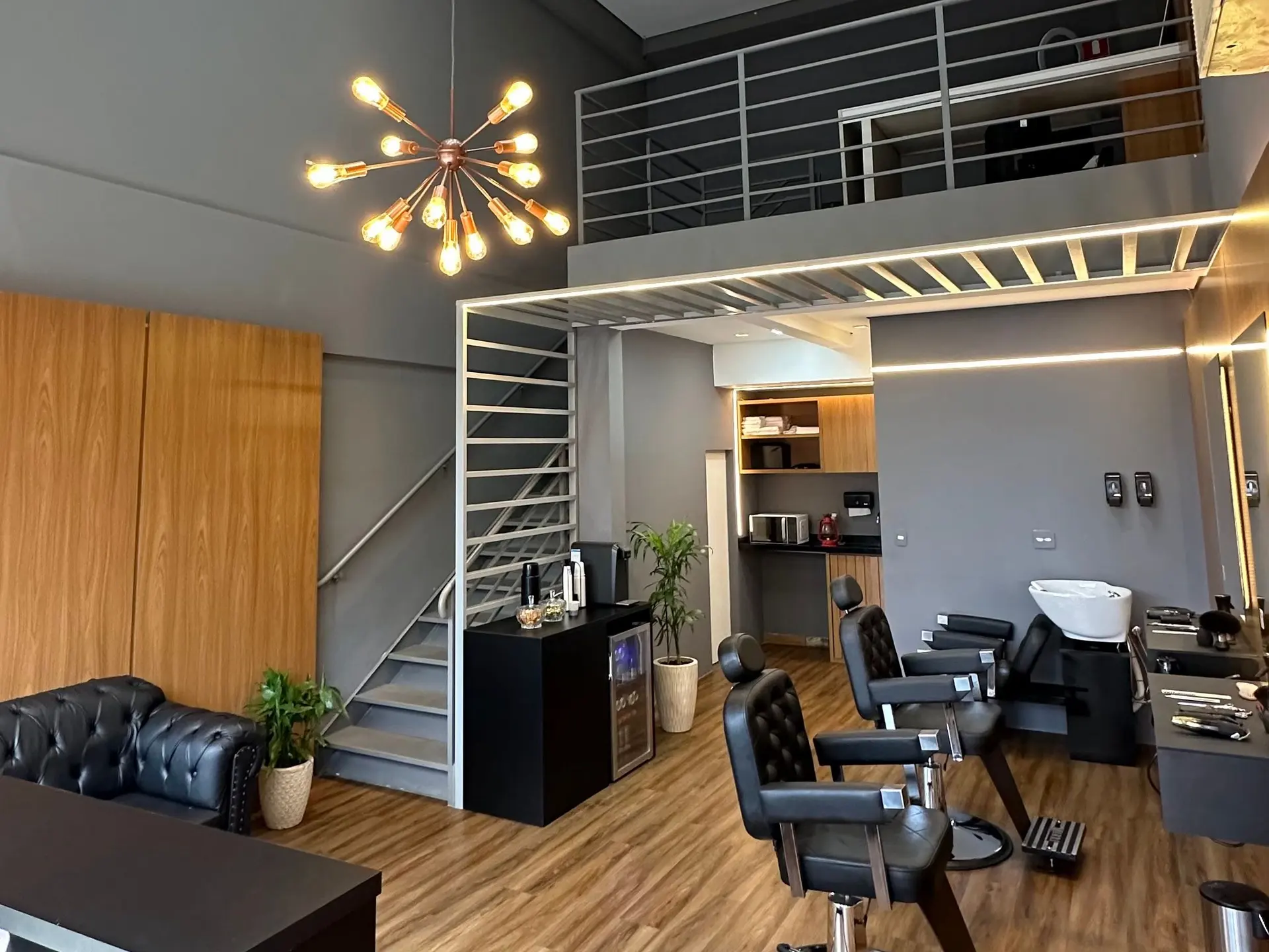 Salão do Garimpo Studio com pé-direito alto, lustre, mezanino e as cadeiras de atendimento